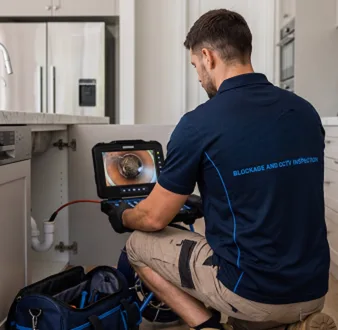 Plumber clearing a blocked toilet in a Turramurra bathroom